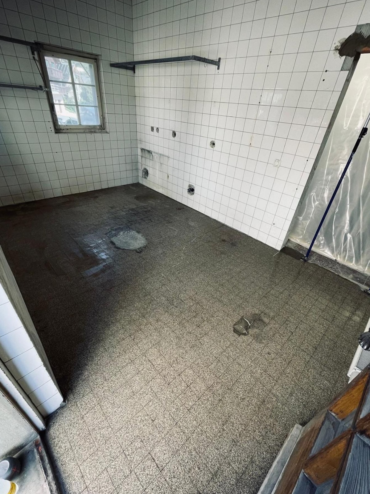 Pièce vide avec carrelage blanc et sol sale.